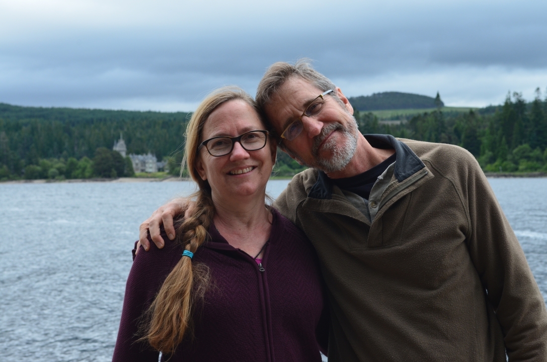 Couple posant au bord d'un lac avec un château en arrière-plan.