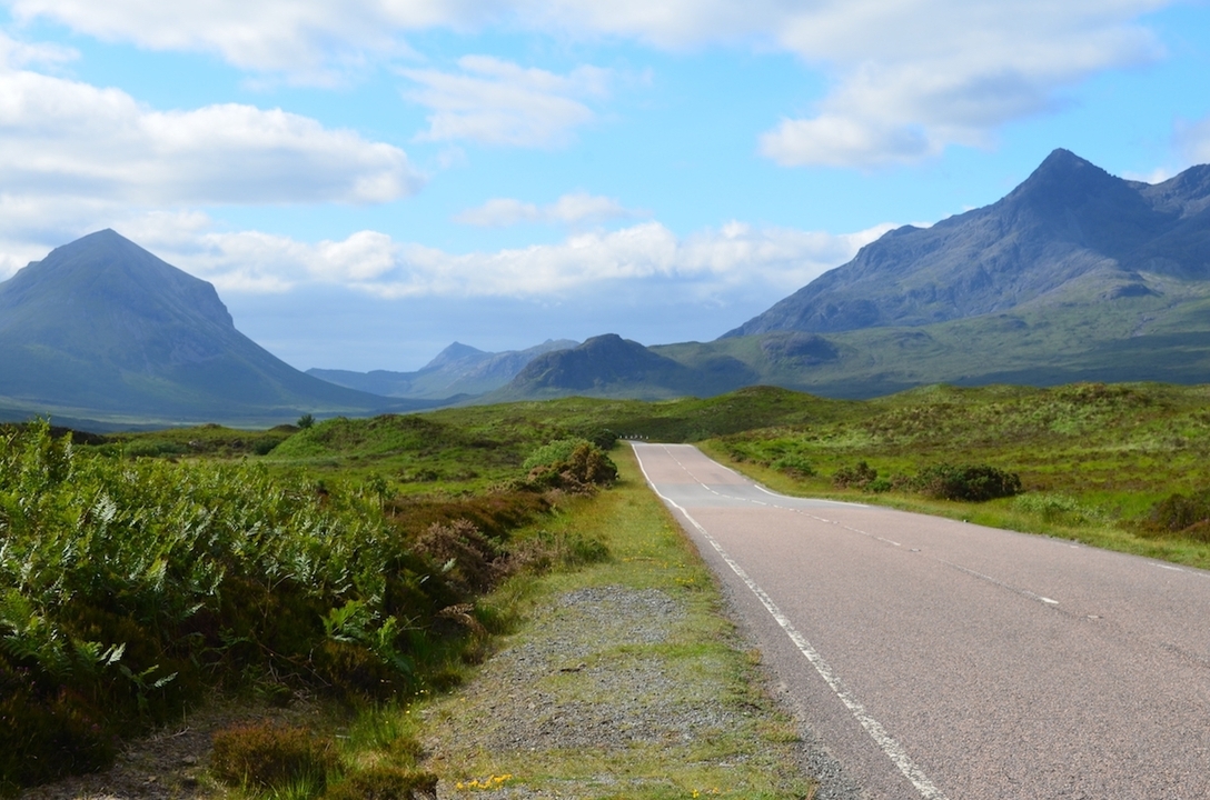 Scenic road leading towards mountains in the highlands.