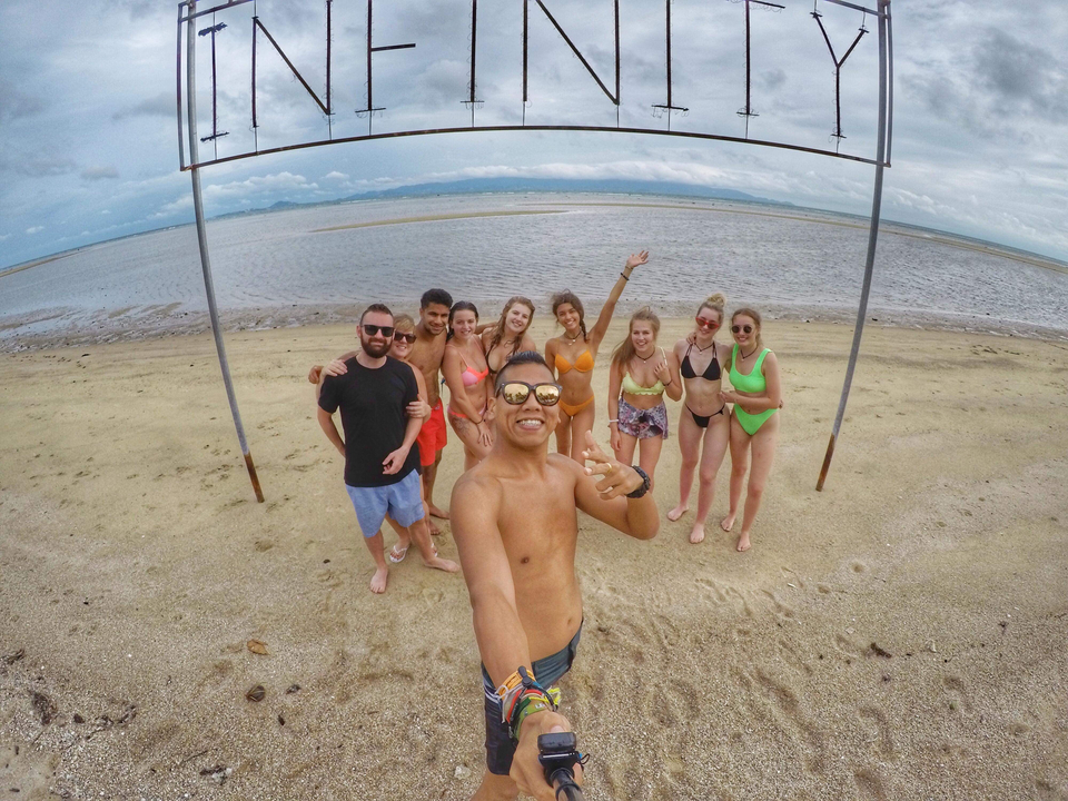 Group posing on a beach with clear skies.