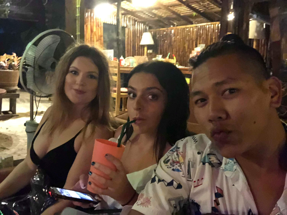 Two women and a man posing with drinks at a cozy venue.
