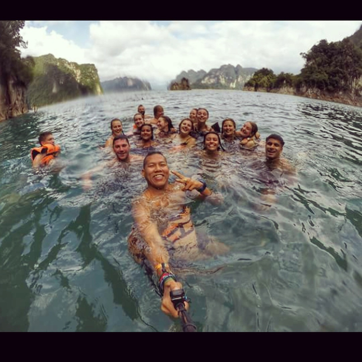 Group of people swimming in a lake surrounded by rocks.