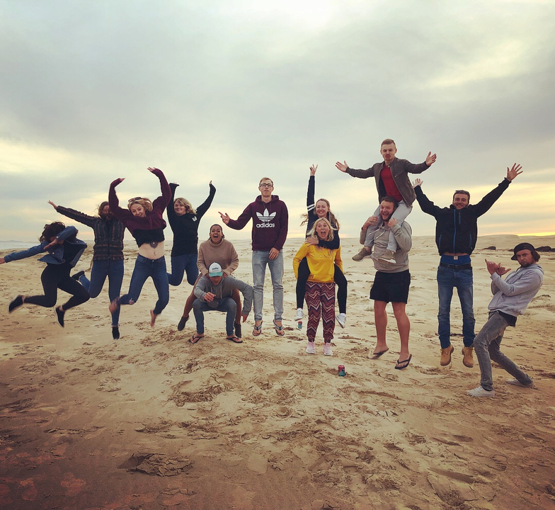 A group of people jumping on a beach.