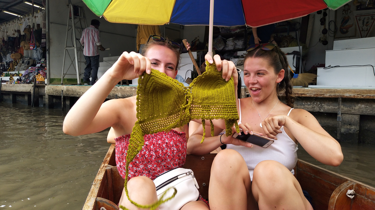 Two women on a boat holding a knitted garment.