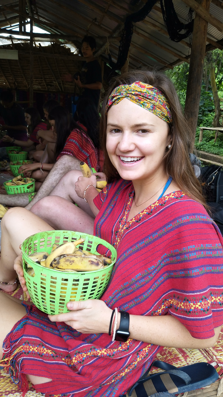 Smiling woman holding a basket of bananas.