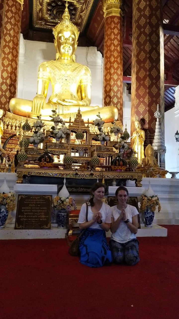 Two people posing in front of a decorative temple shrine.