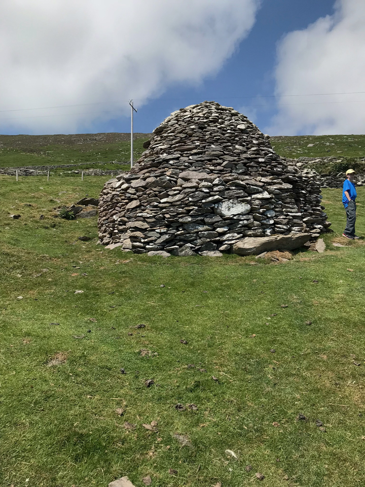 Circular stone structure on grassy landscape.