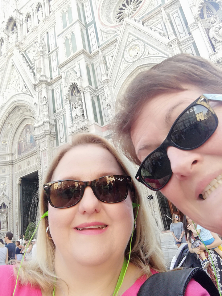 Deux femmes prenant un selfie devant un bâtiment orné.
