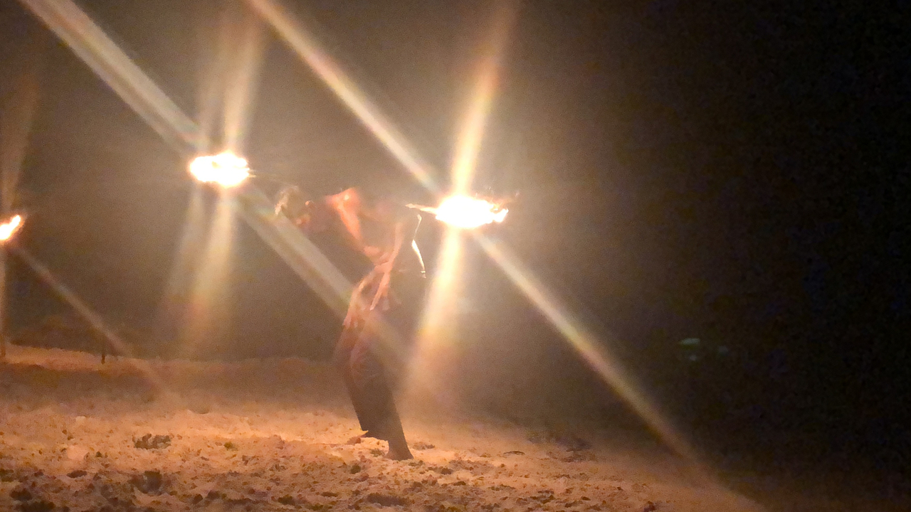 Personne exécutant une danse du feu sur la plage la nuit.