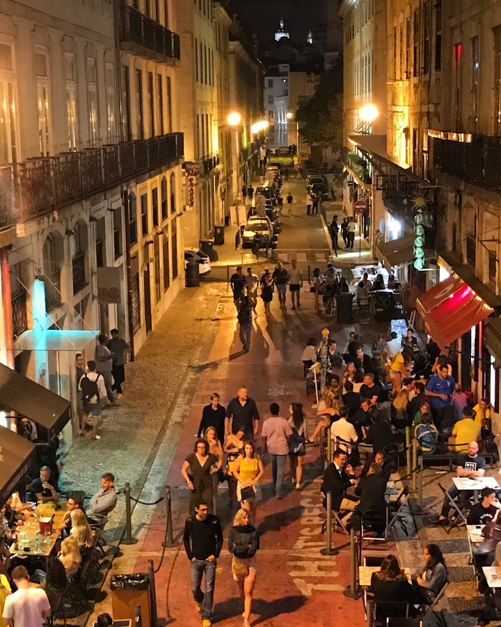 Rue animée la nuit avec des gens qui dînent et se promènent.