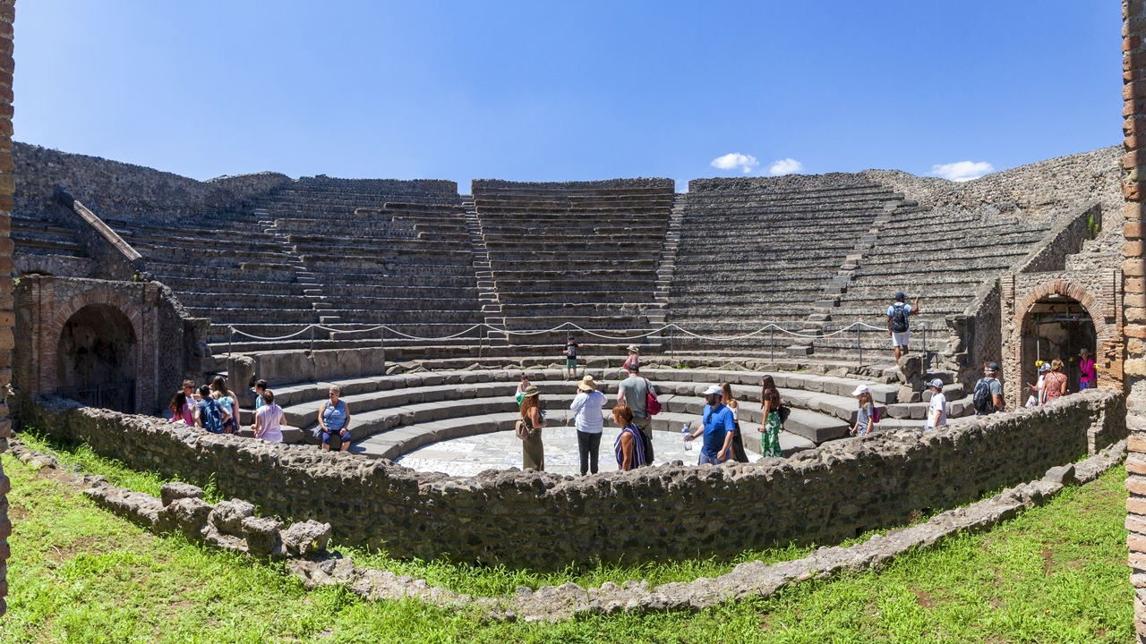Touristes explorant un amphithéâtre antique.