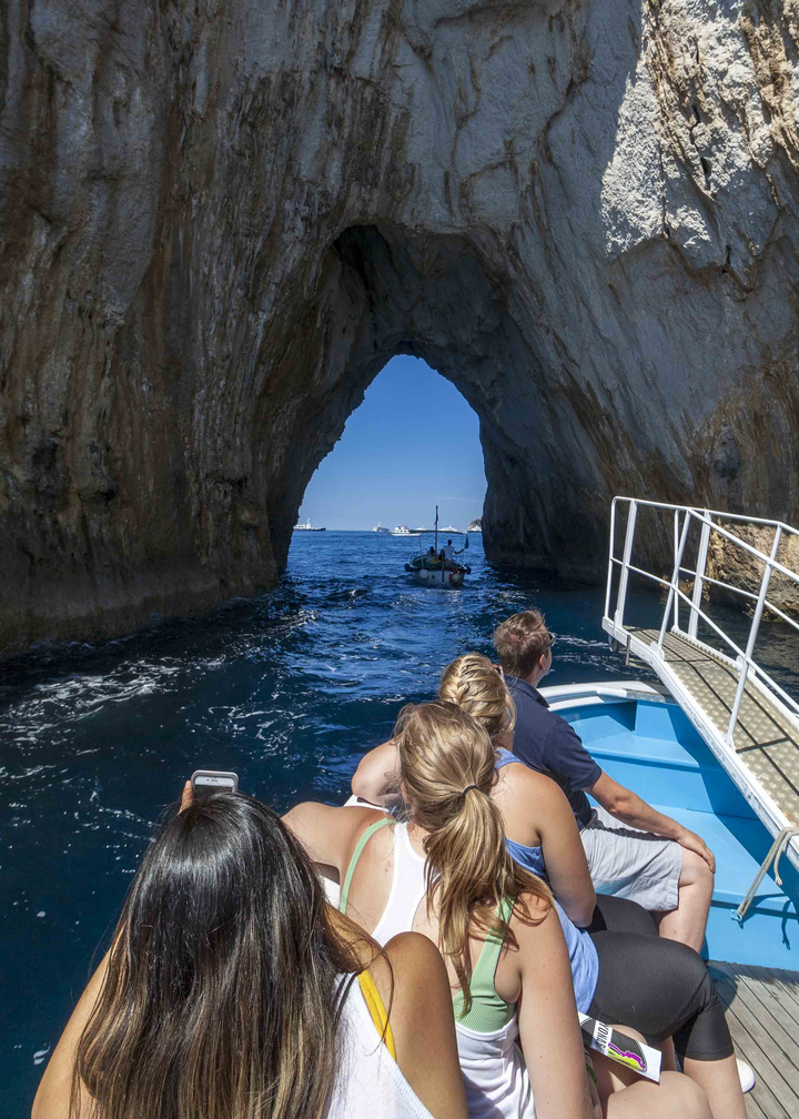 Passagers d'un bateau pénétrant dans une grotte marine.