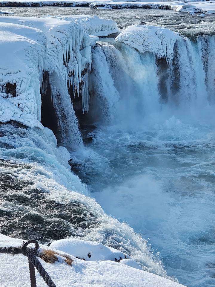 Waterfall frozen in places, tilting down a cliff.