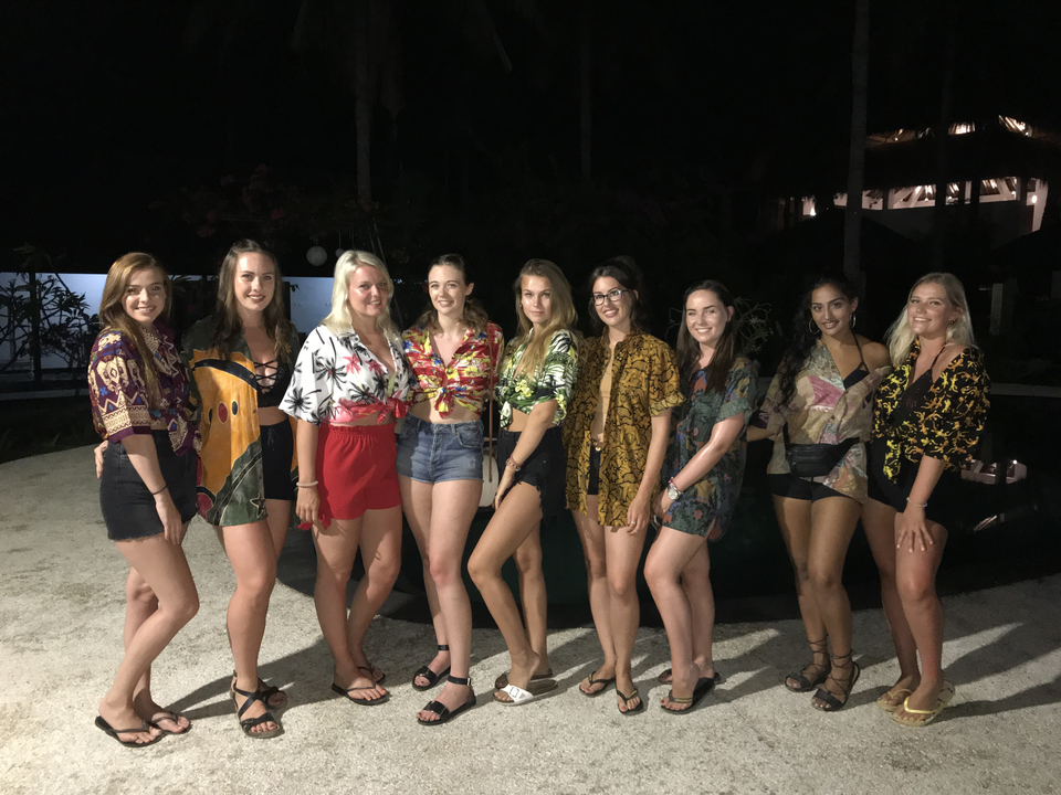 Group of women posing in casual attire at night.