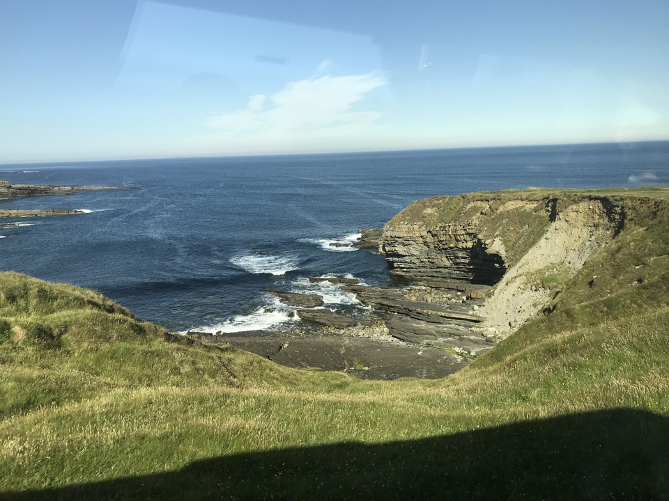 Vue à flanc de falaise avec des vagues se brisant contre les rochers.
