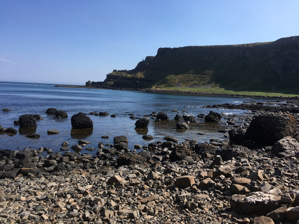 Formations rocheuses côtières avec une falaise en arrière-plan.