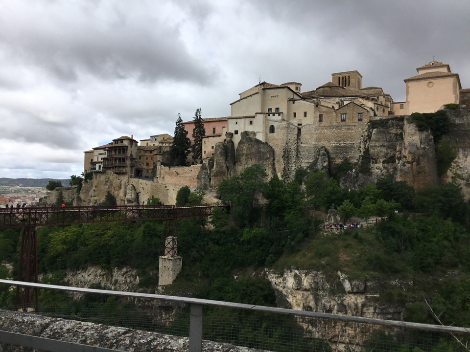 Ville historique construite sur des falaises rocheuses avec un pont au premier plan.