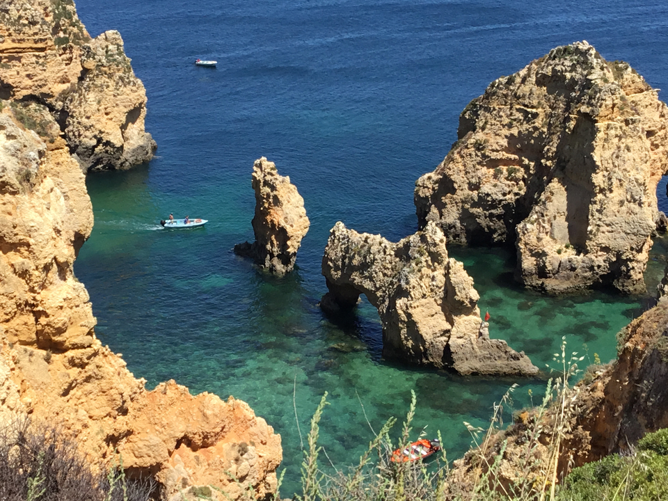 Côte rocheuse avec un petit bateau sur une eau turquoise.