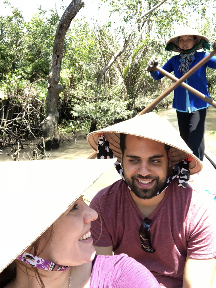 Gros plan d'une personne portant un chapeau conique sur un bateau dans une rivière.