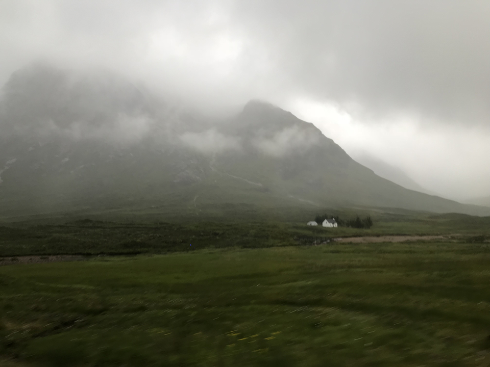 Paysage de montagne brumeux avec un bâtiment éloigné.