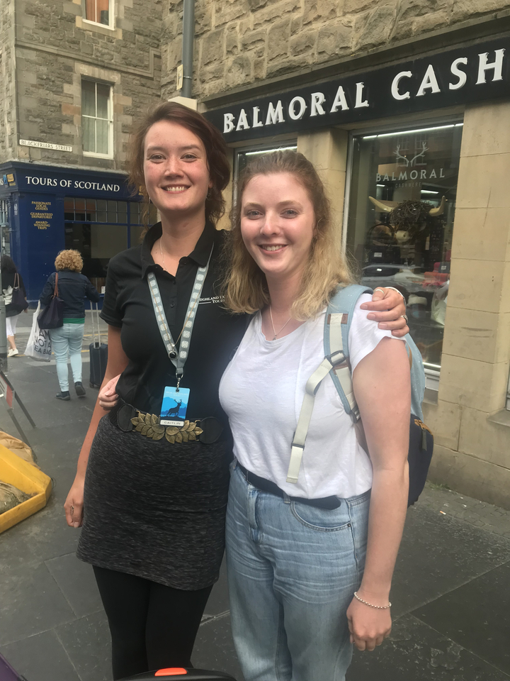 Deux femmes souriantes, dont l'une porte un cordon de visite.
