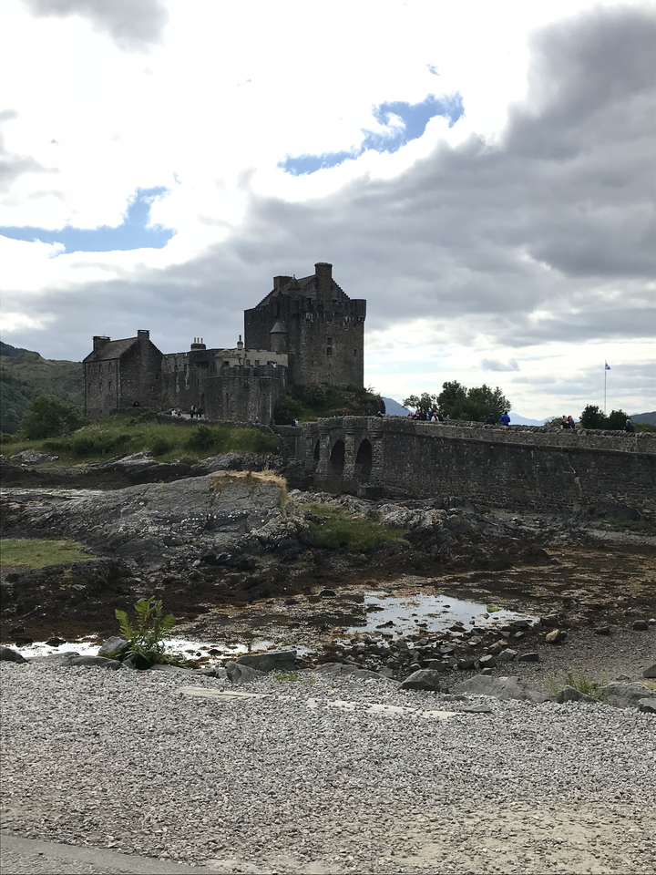 Le château d'Eilean Donan avec un pont de pierre et un arrière-plan montagneux.