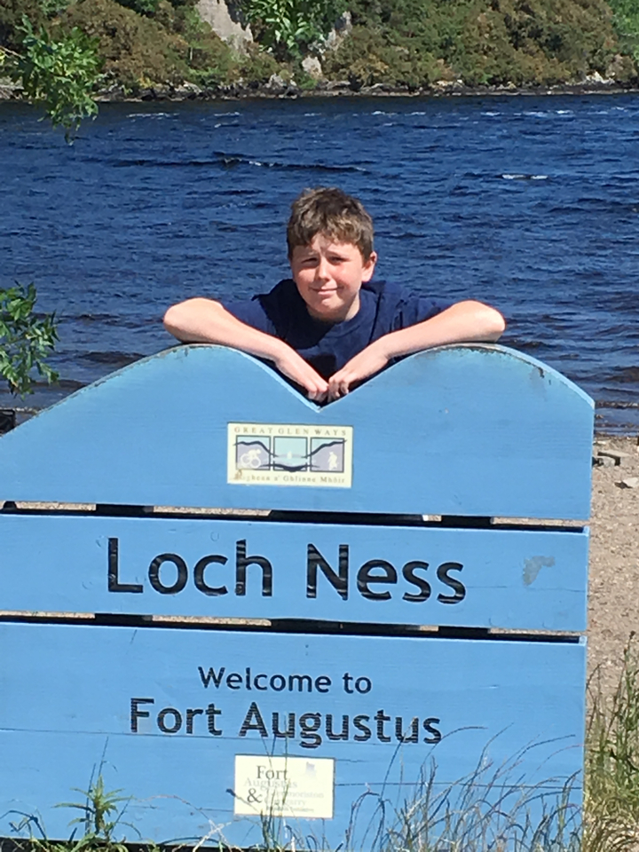 Personne posant avec un panneau indiquant "Loch Ness".