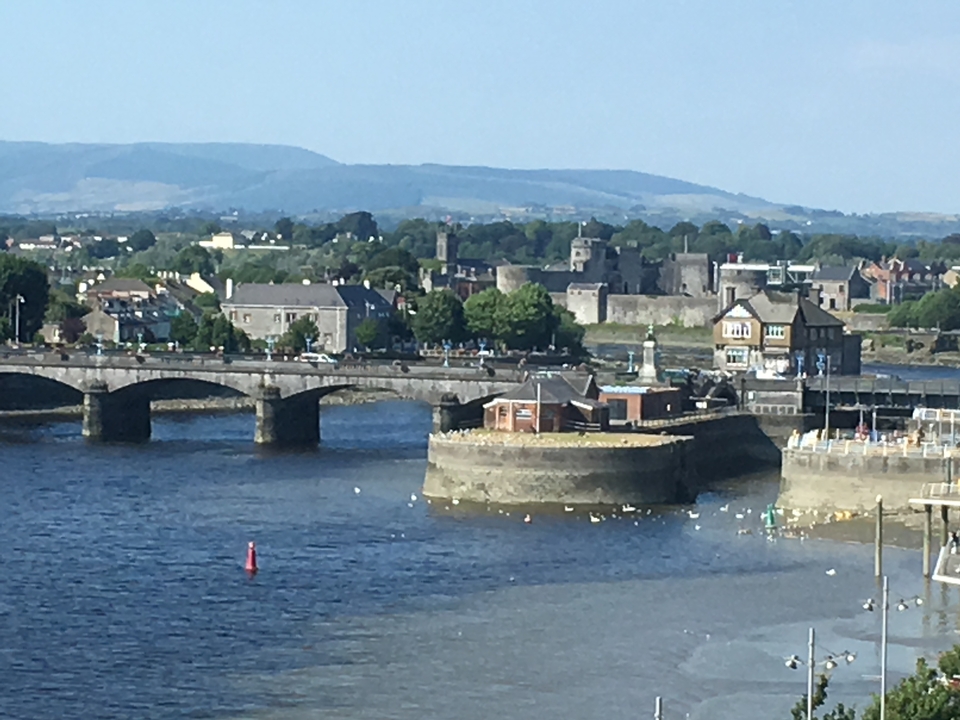 Vue panoramique d'une rivière et d'un pont avec des bâtiments et des collines.