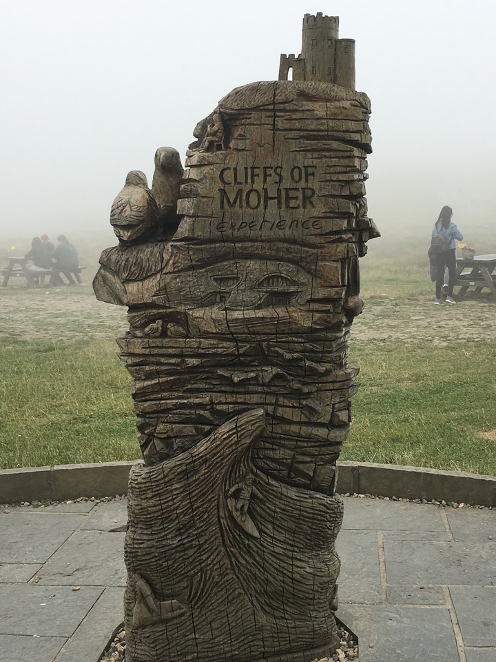 A carved wooden statue with people in the background.