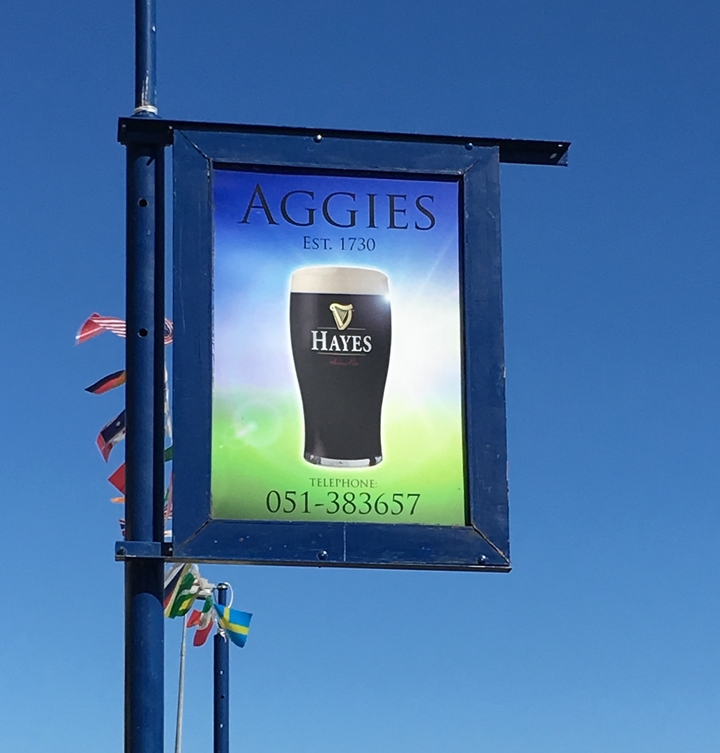 Une enseigne de pub annonçant la Guinness dans un endroit ensoleillé.