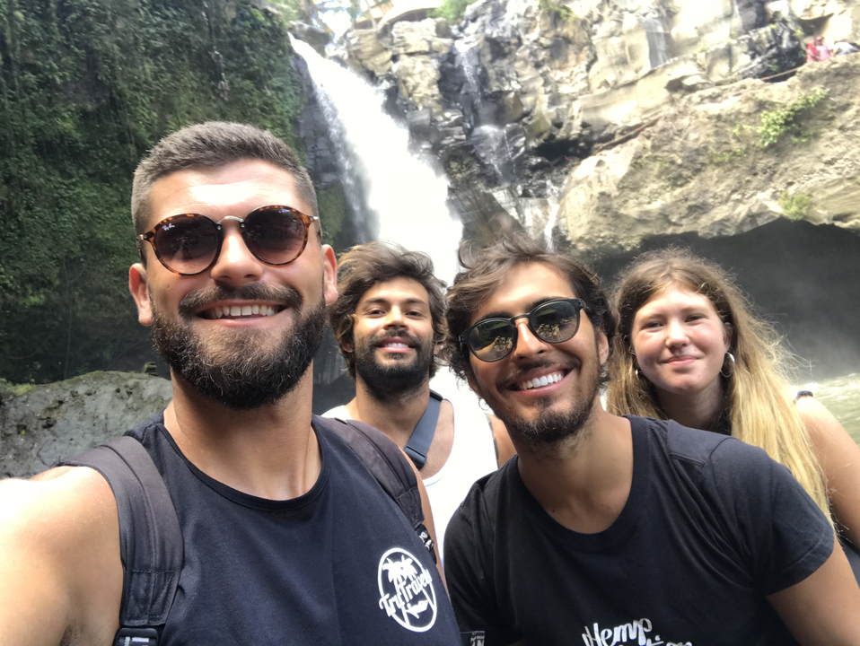 Group of people posing in front of a waterfall.