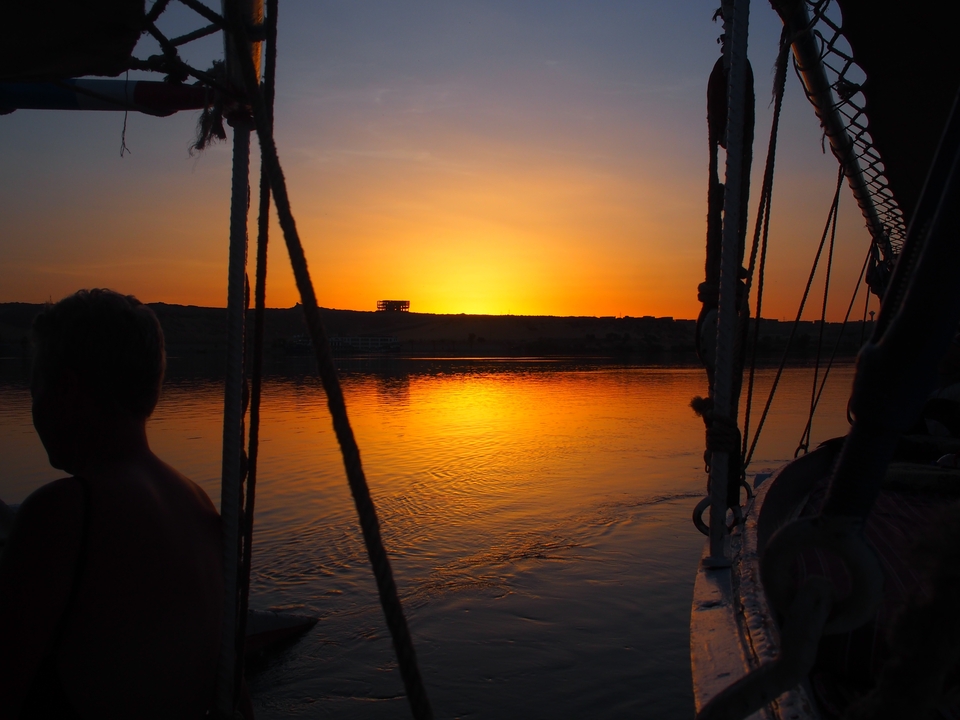 Silhouette d'une personne sur un bateau au coucher du soleil sur une rivière.