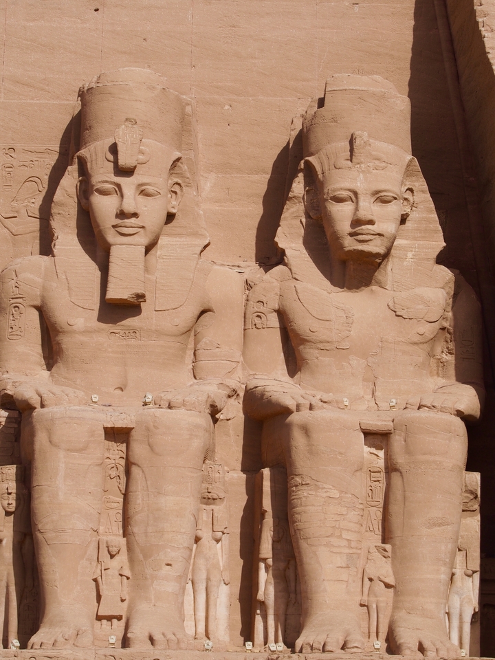 Gros plan sur deux statues sculptées dans une paroi rocheuse.