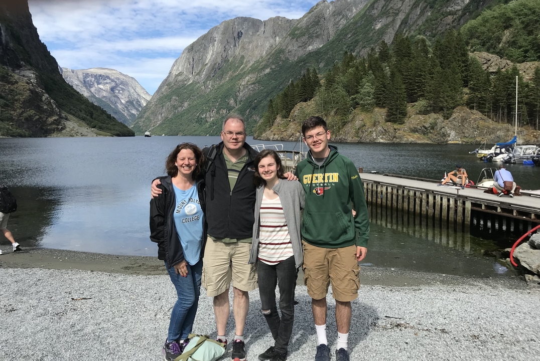 Famille posant sur un quai avec un fjord et des montagnes en arrière-plan.