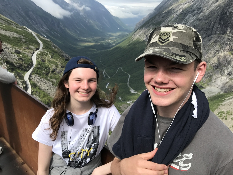 Deux personnes souriant avec une vallée et une route en contrebas.