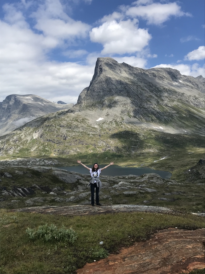 Personne debout, les bras levés, dans un paysage montagneux.