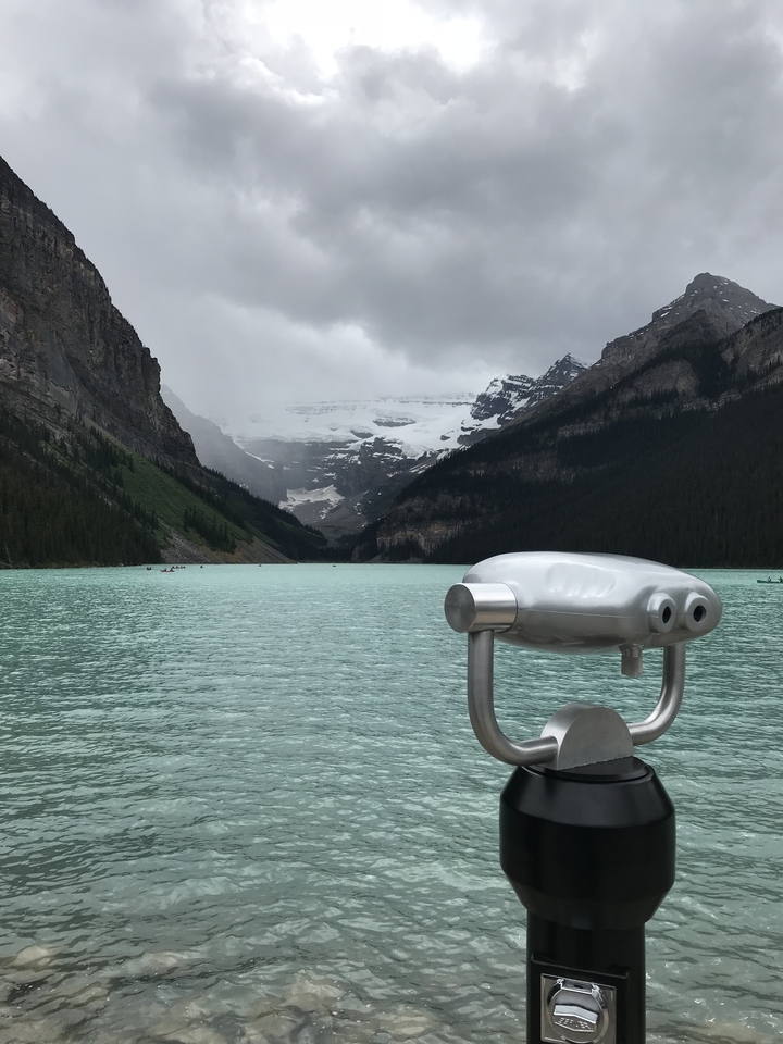 Lac alimenté par des glaciers et entouré de montagnes sous un ciel nuageux.
