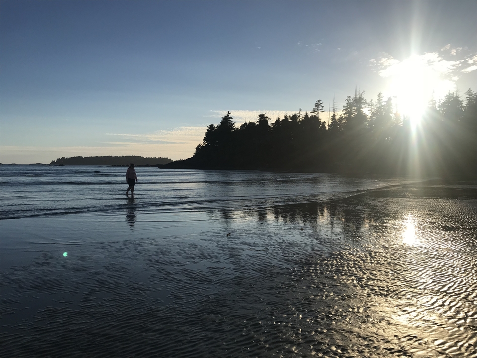 Silhouette marchant sur une plage au coucher du soleil.