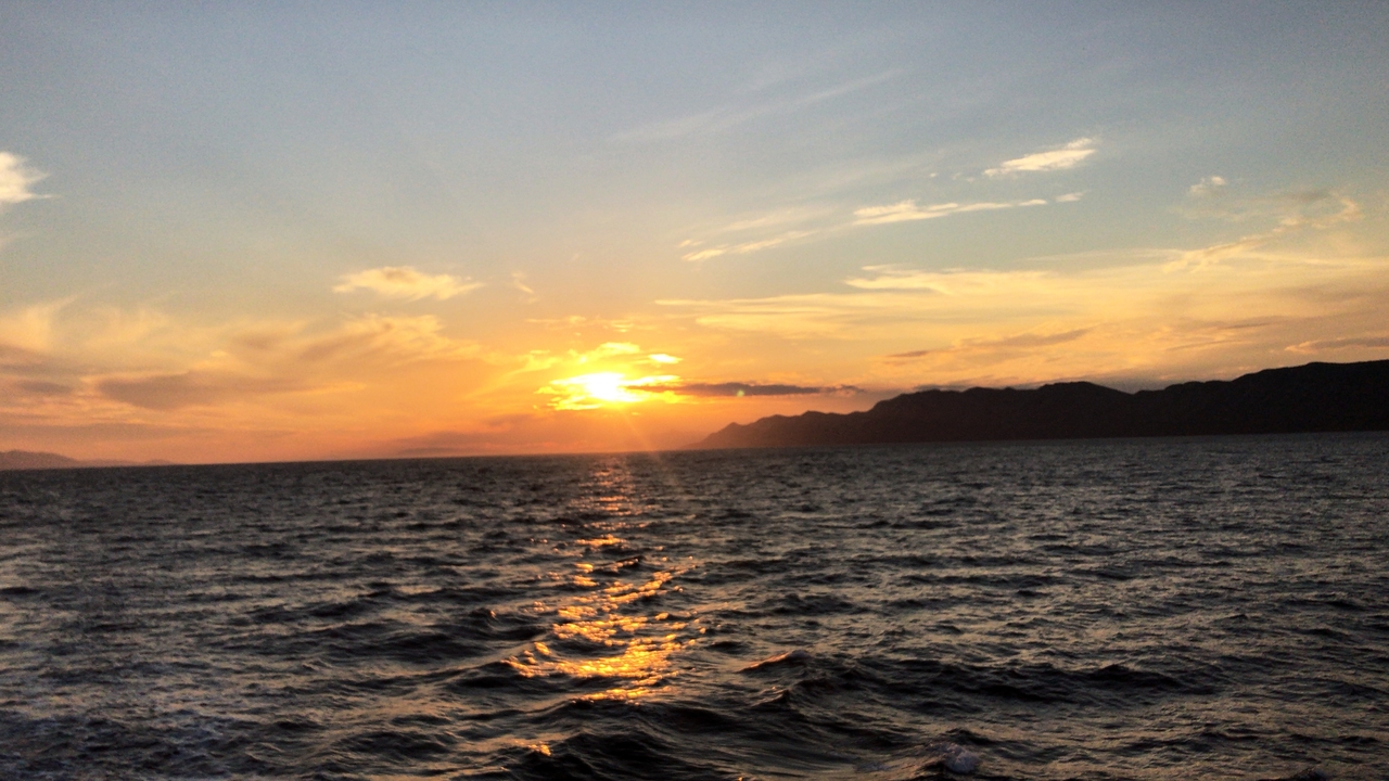 Sunset over the sea with a cloudy sky.