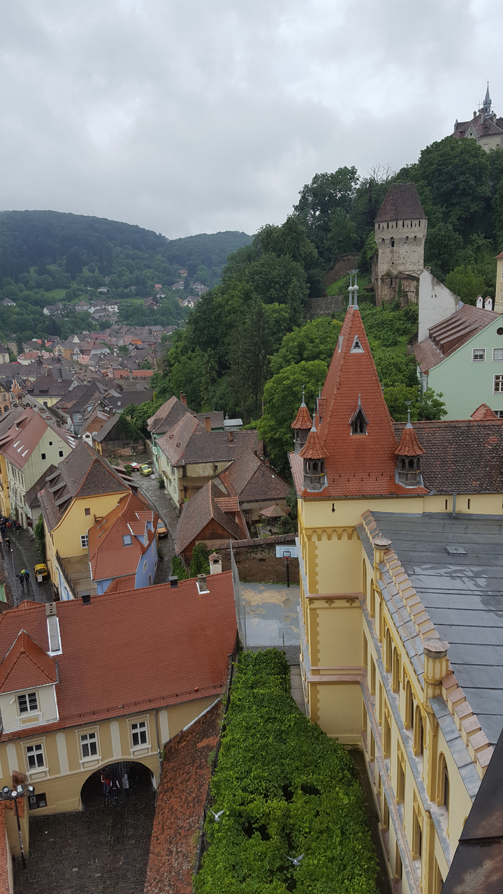 Vue aérienne d'une ville vallonnée avec des bâtiments uniques aux toits rouges.
