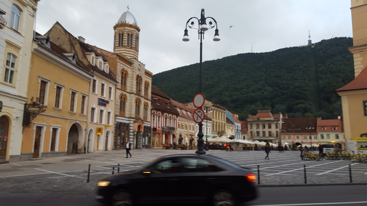 Place de la ville avec une architecture historique et une montagne en arrière-plan.