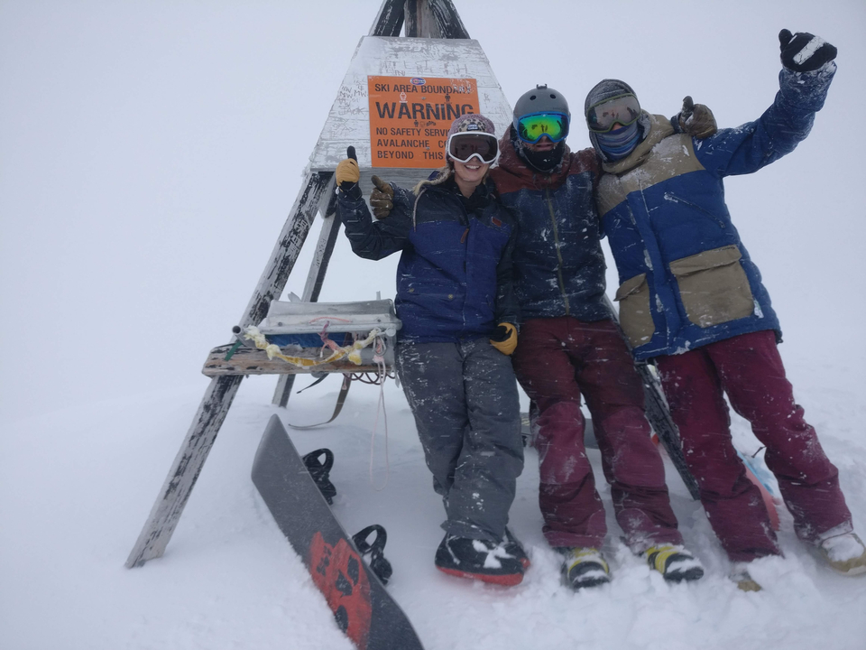 Groupe de snowboarders posant sur une montagne enneigée.