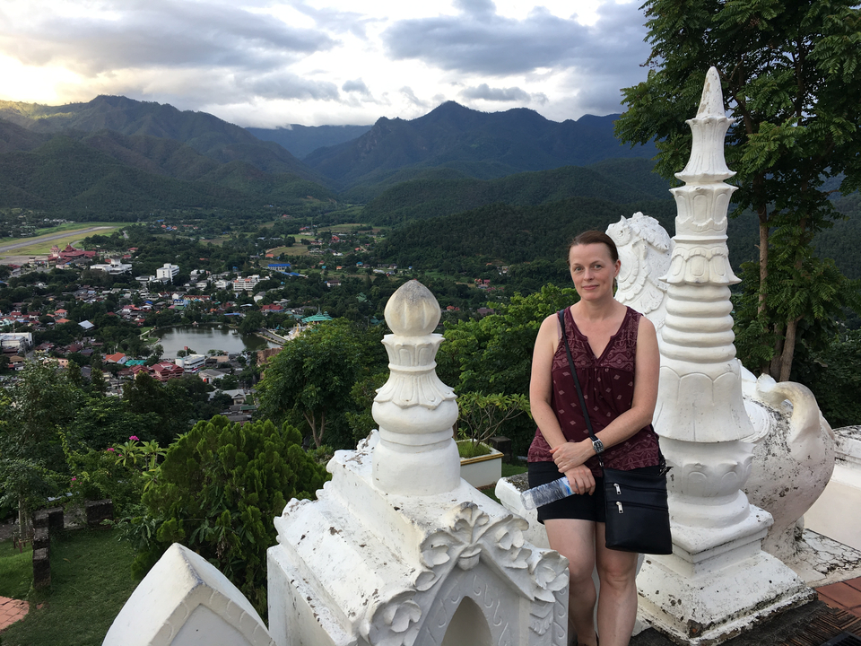 Femme posant avec un paysage montagneux, une vue de la ville et de l'architecture en arrière-plan.