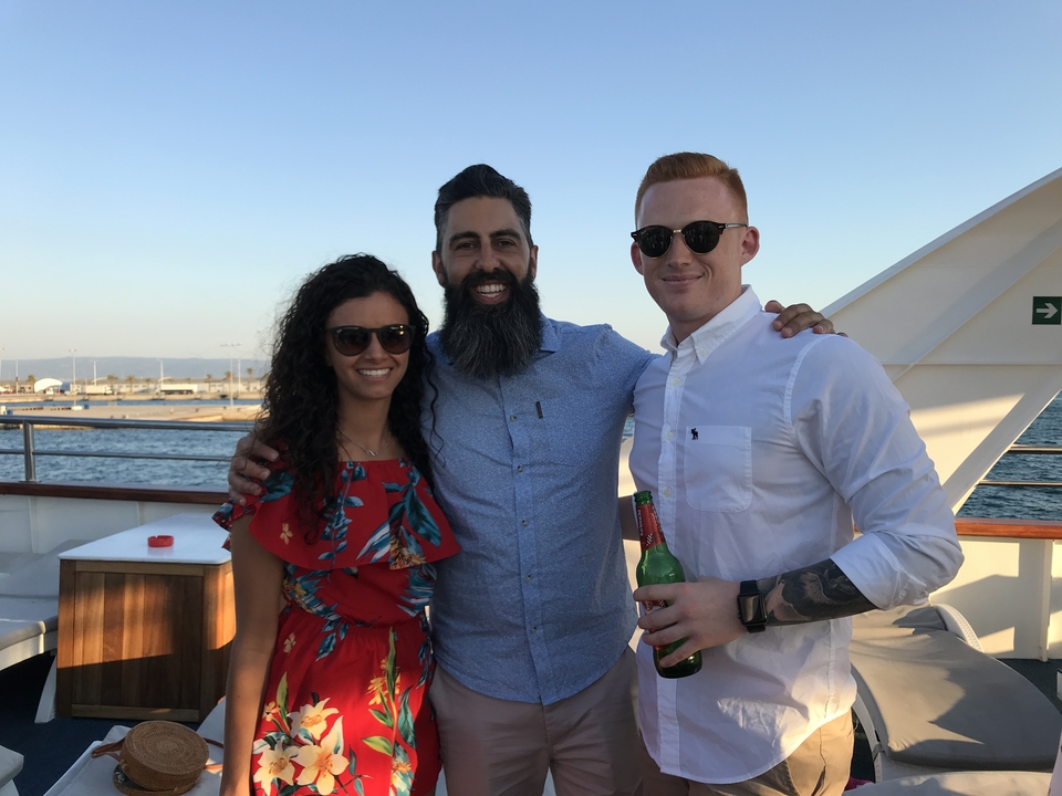 Trois personnes posant sur un bateau, souriant et profitant de la lumière du soleil.