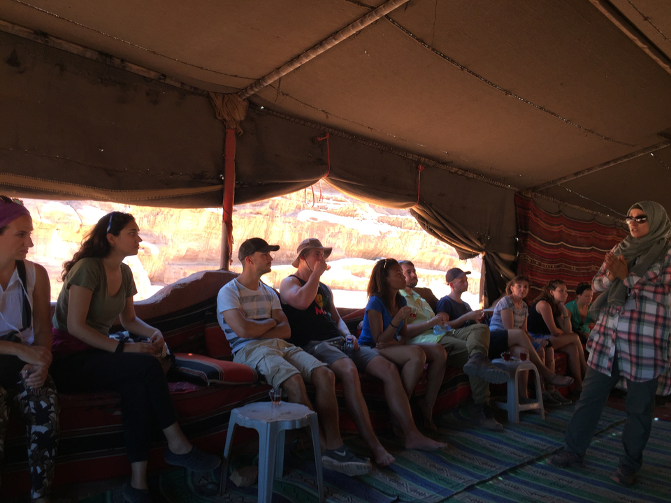 Un groupe de personnes assises à l'intérieur d'une tente de style bédouin dans le désert.