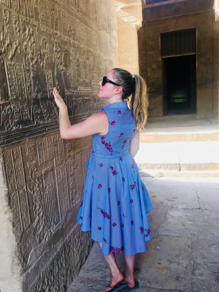 Femme regardant d'anciennes gravures sur un mur.