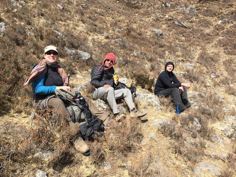 Trois personnes se reposant sur une colline rocheuse.
