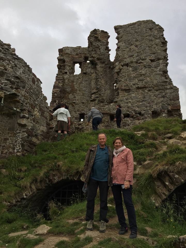 Des gens explorant des ruines avec des murs de pierre.