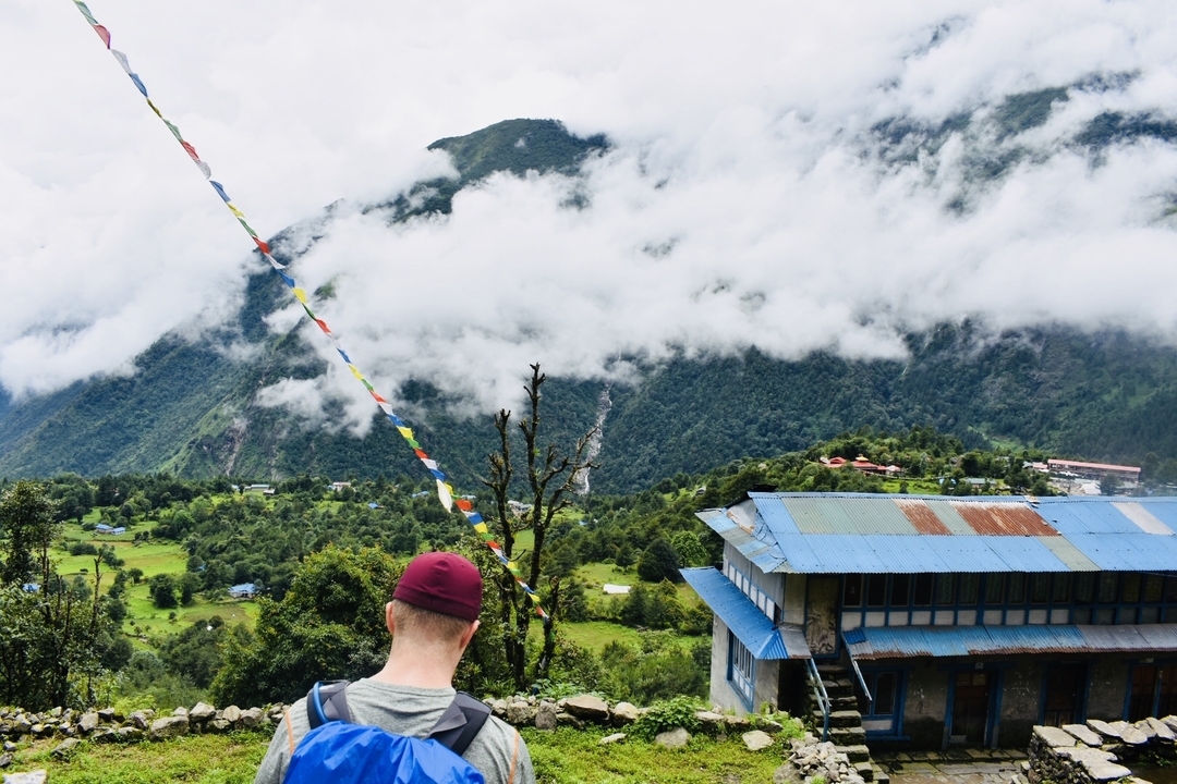 Personne contemplant une vallée dans les montagnes avec des drapeaux de prière.