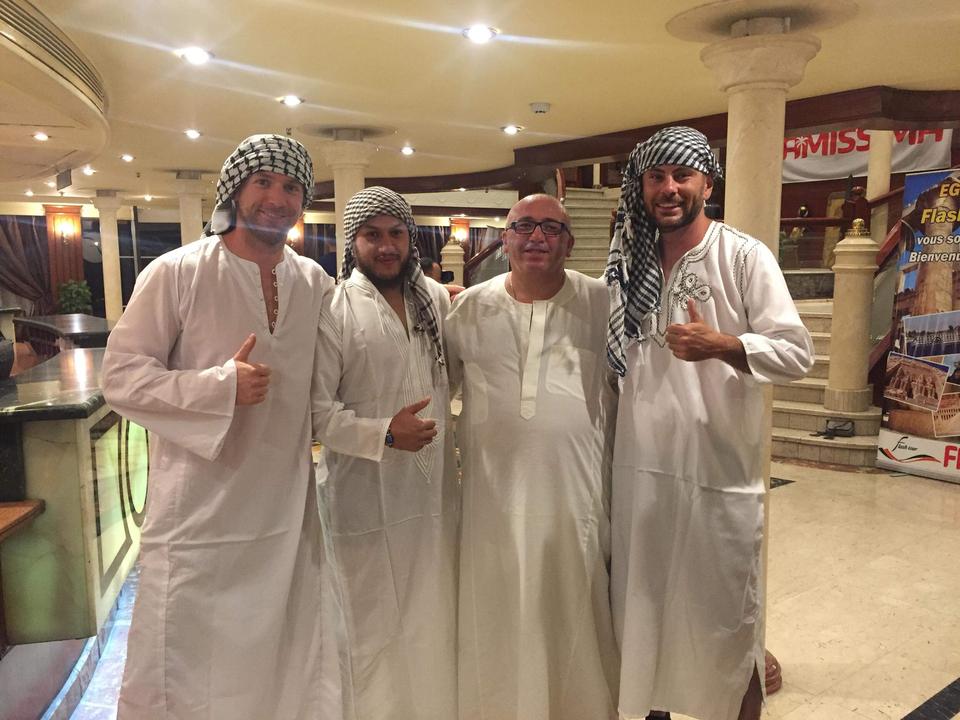 Groupe de personnes vêtues d'habits traditionnels à l'intérieur d'un bâtiment.