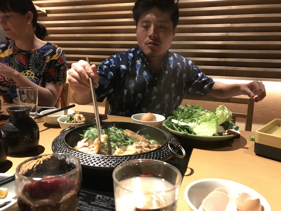 Personne qui cuisine avec des baguettes à une table avec des amis.